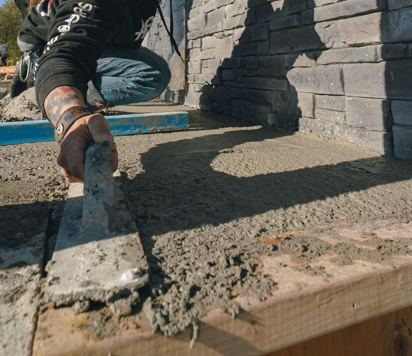 Un homme utilise une truelle pour étaler du béton sur une surface en bois