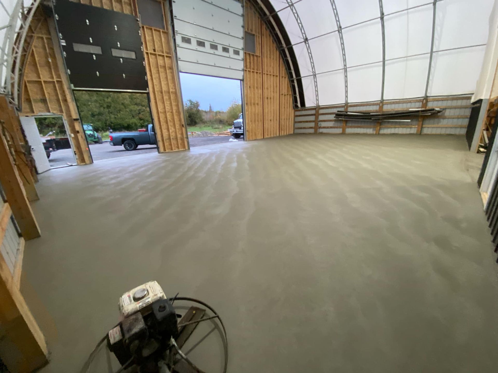 A large warehouse with a concrete floor and a large garage door.