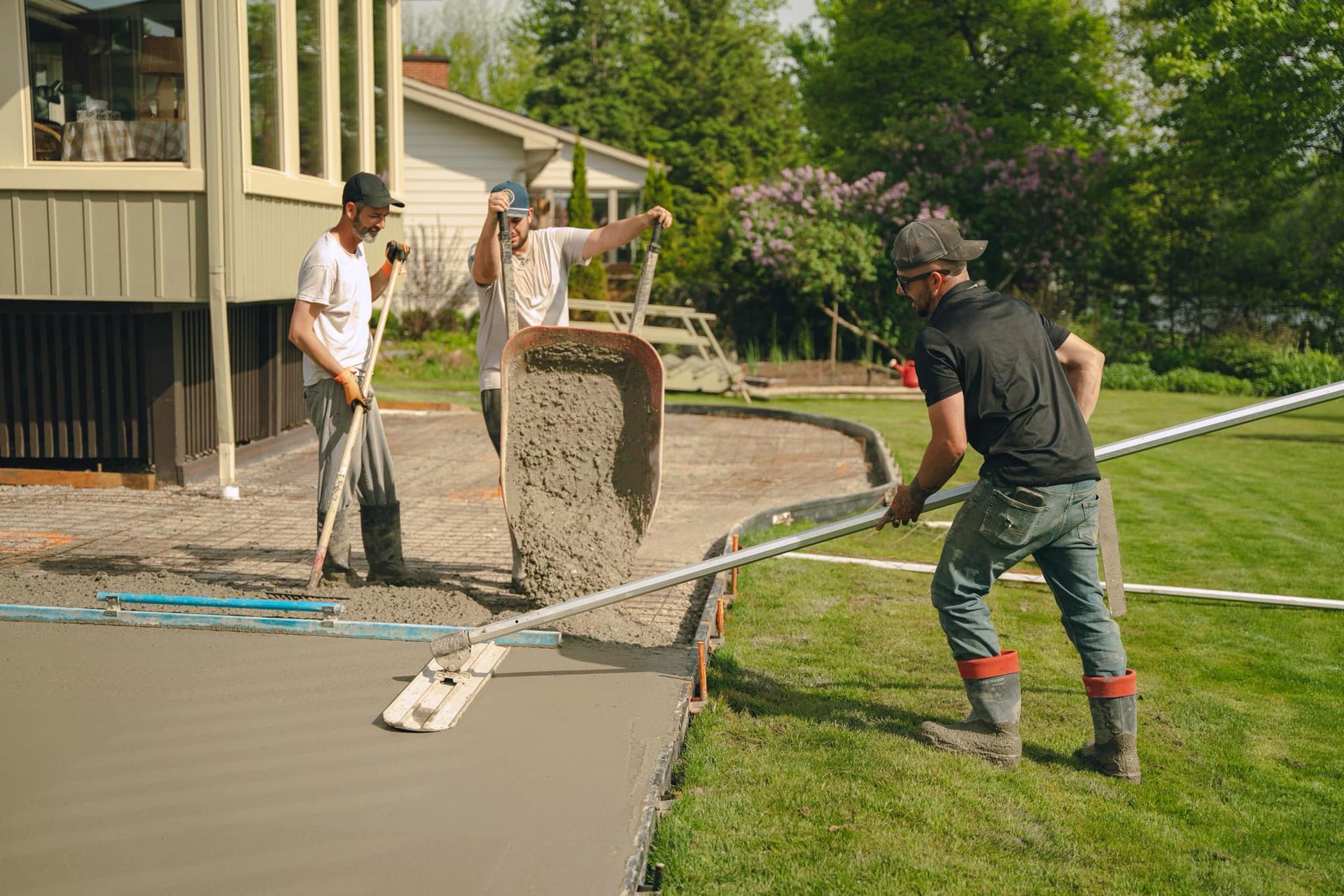 A group of men are working on a concrete driveway.
