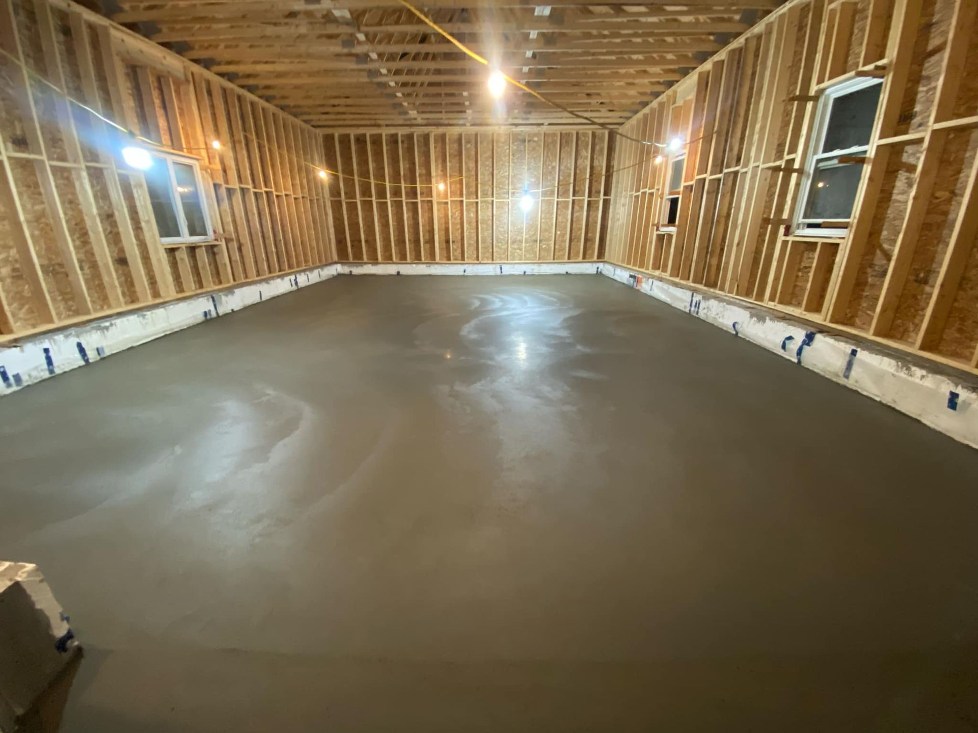 A large room with a concrete floor and walls in a house under construction.