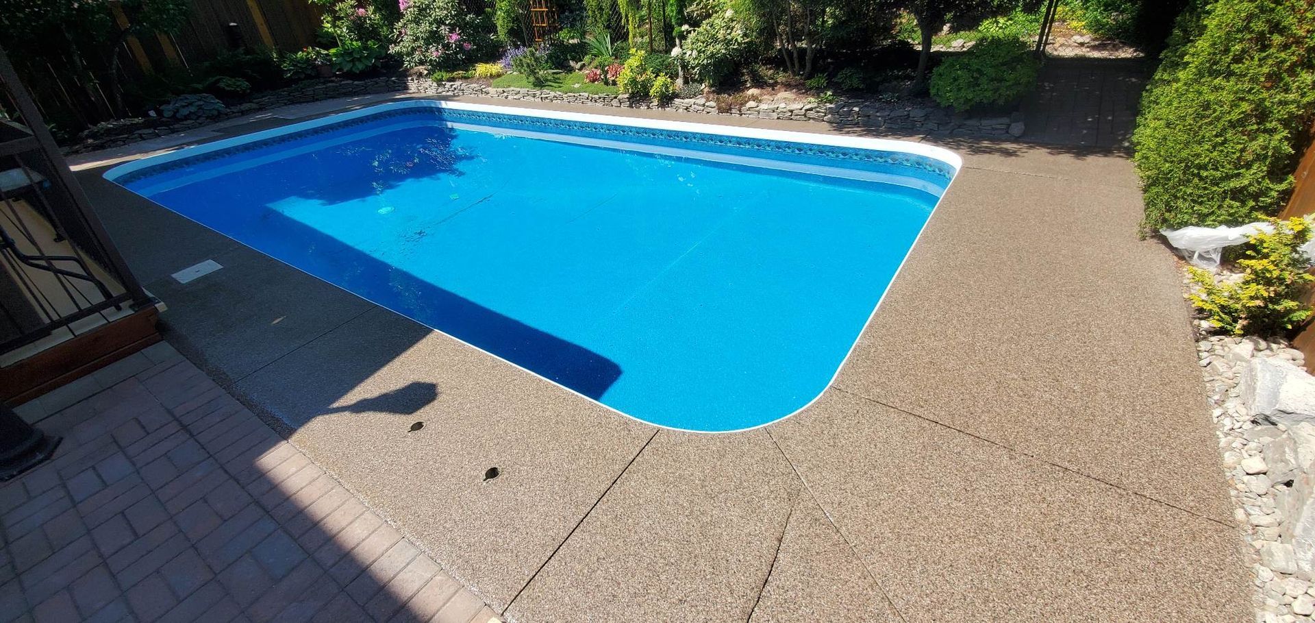 A large swimming pool is sitting on top of a concrete patio.