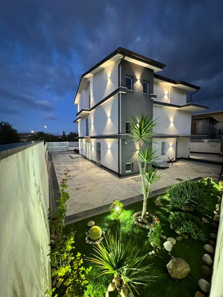 Una grande casa bianca con tante finestre è illuminata di notte.