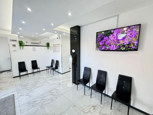 Una sala d'attesa con sedie e una televisione alla parete.