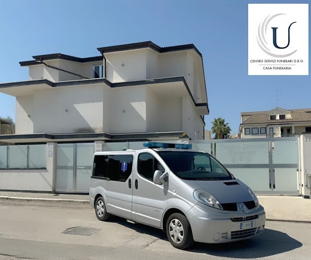 Un furgone argentato è parcheggiato davanti a un grande edificio bianco.