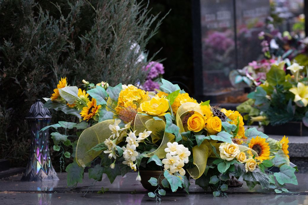 Un vaso pieno di fiori gialli è appoggiato su una tomba.