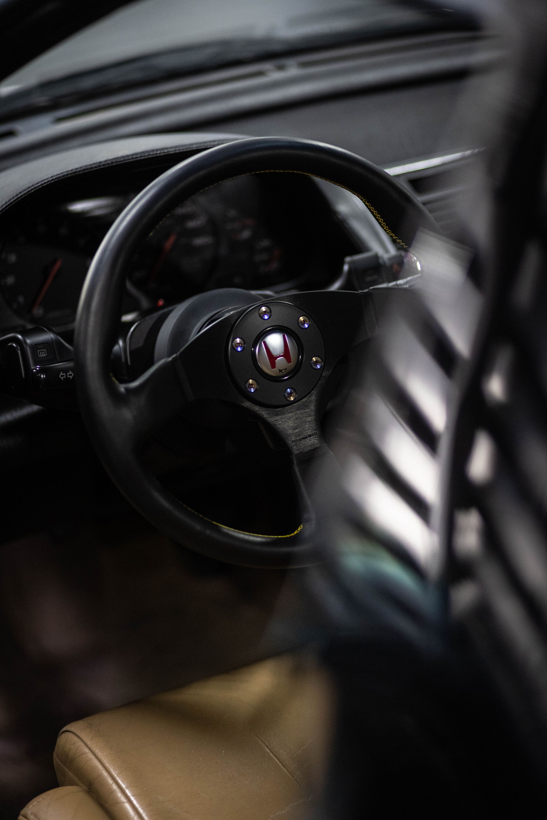 Close-up of a car’s black steering wheel and tan leather seat interior