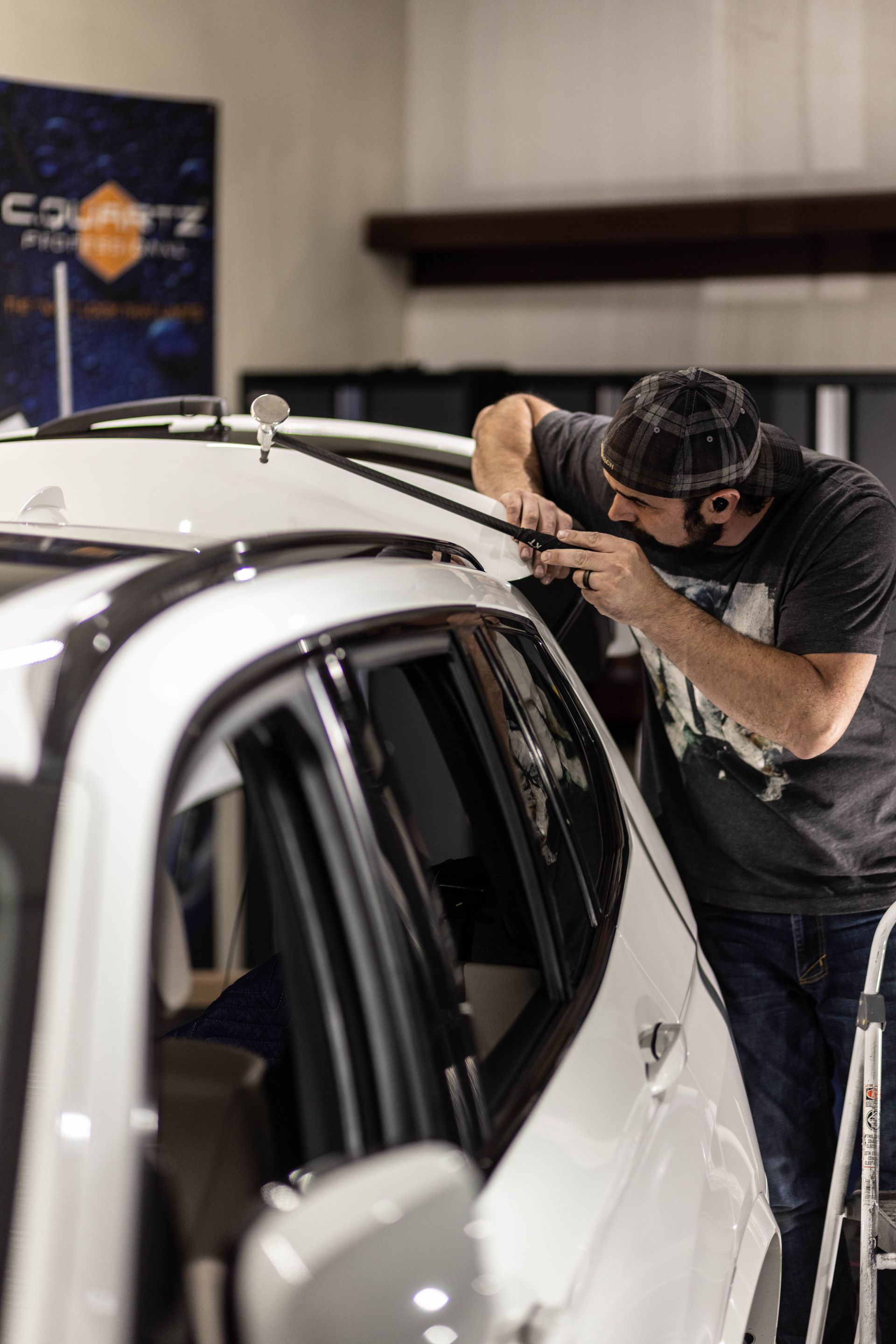 Technician polishing a white car in a garage