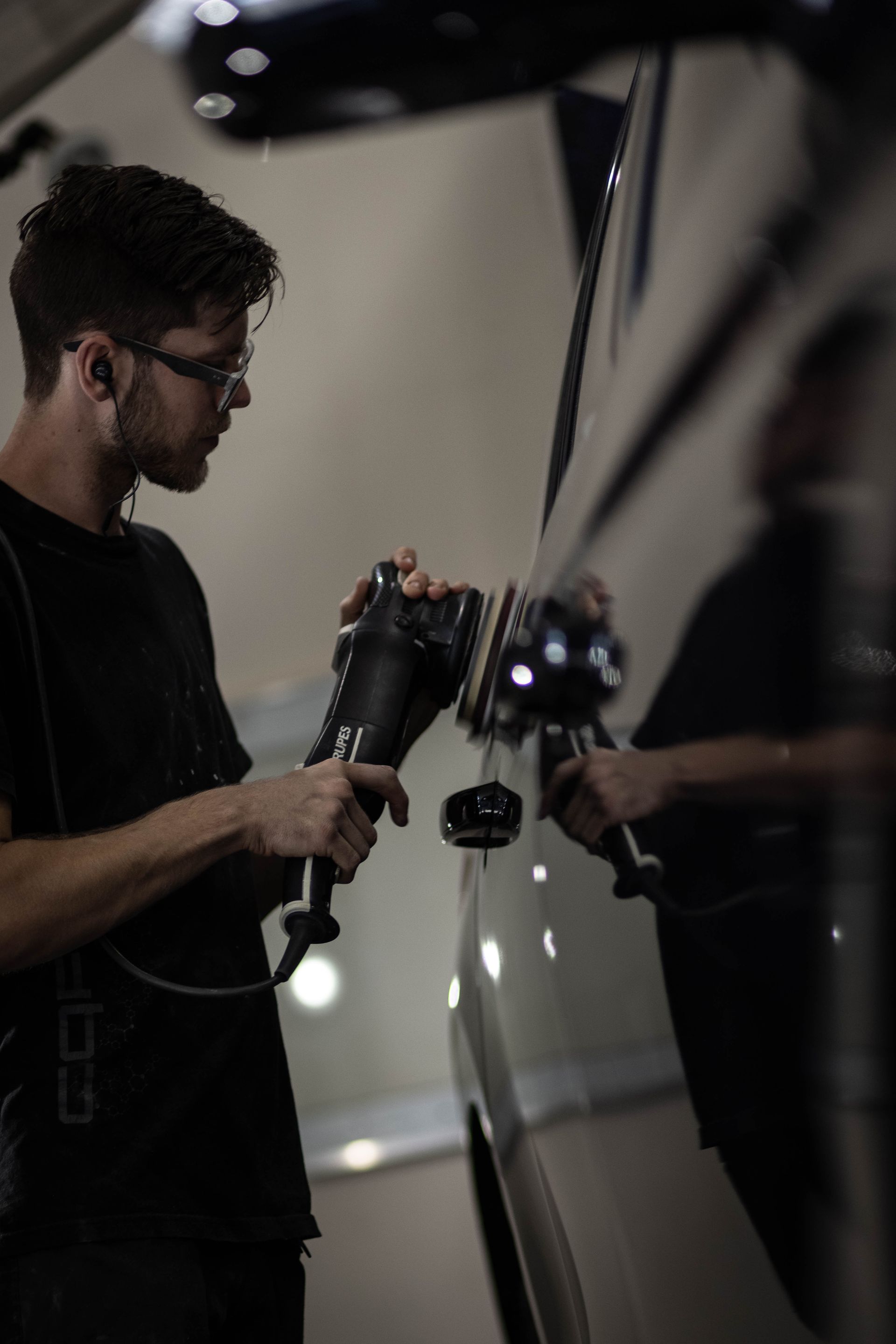 Person using a power tool to work on a car door in a dim garage