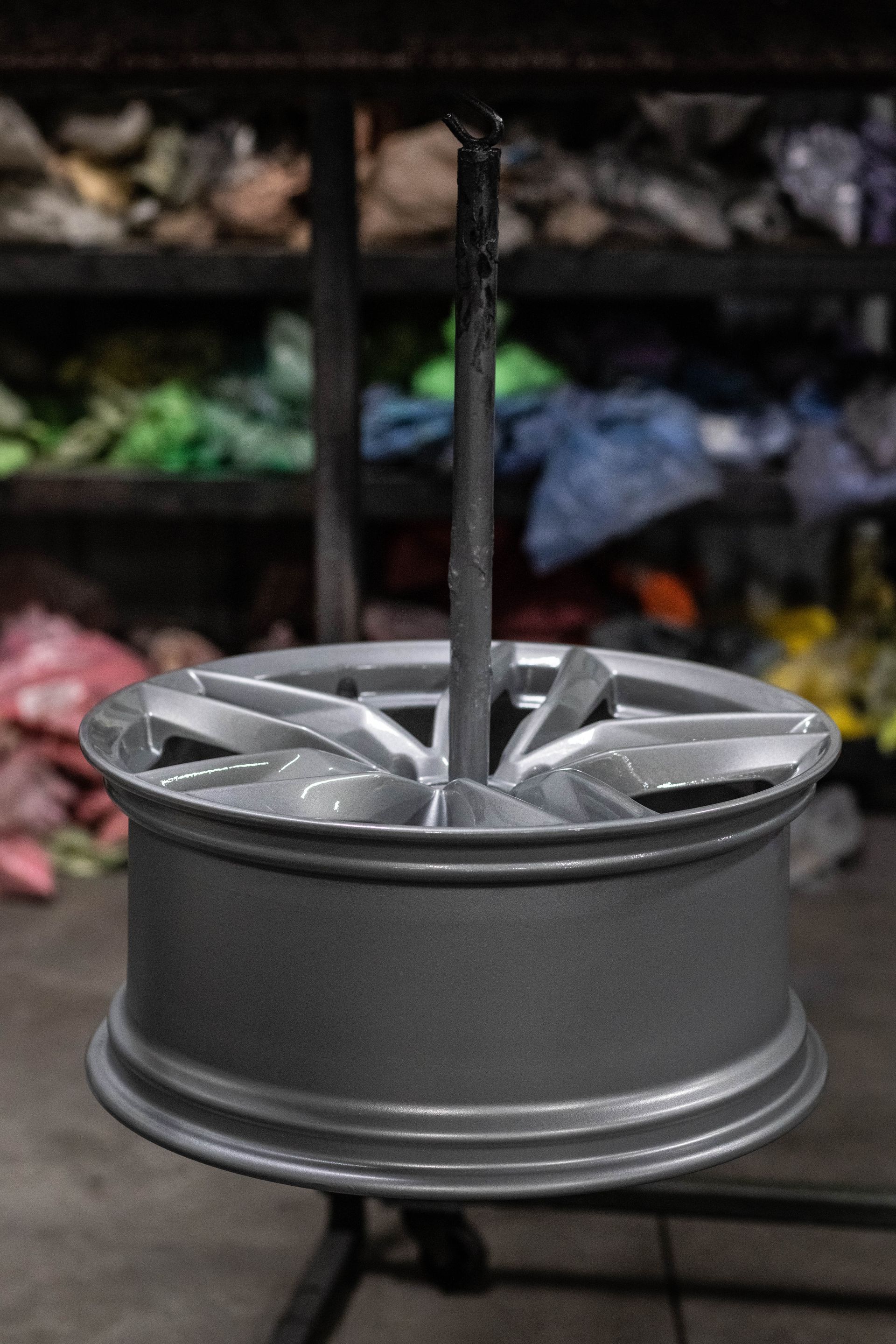 Silver car wheel rim on a table with a blurred shelf of fabric in the background