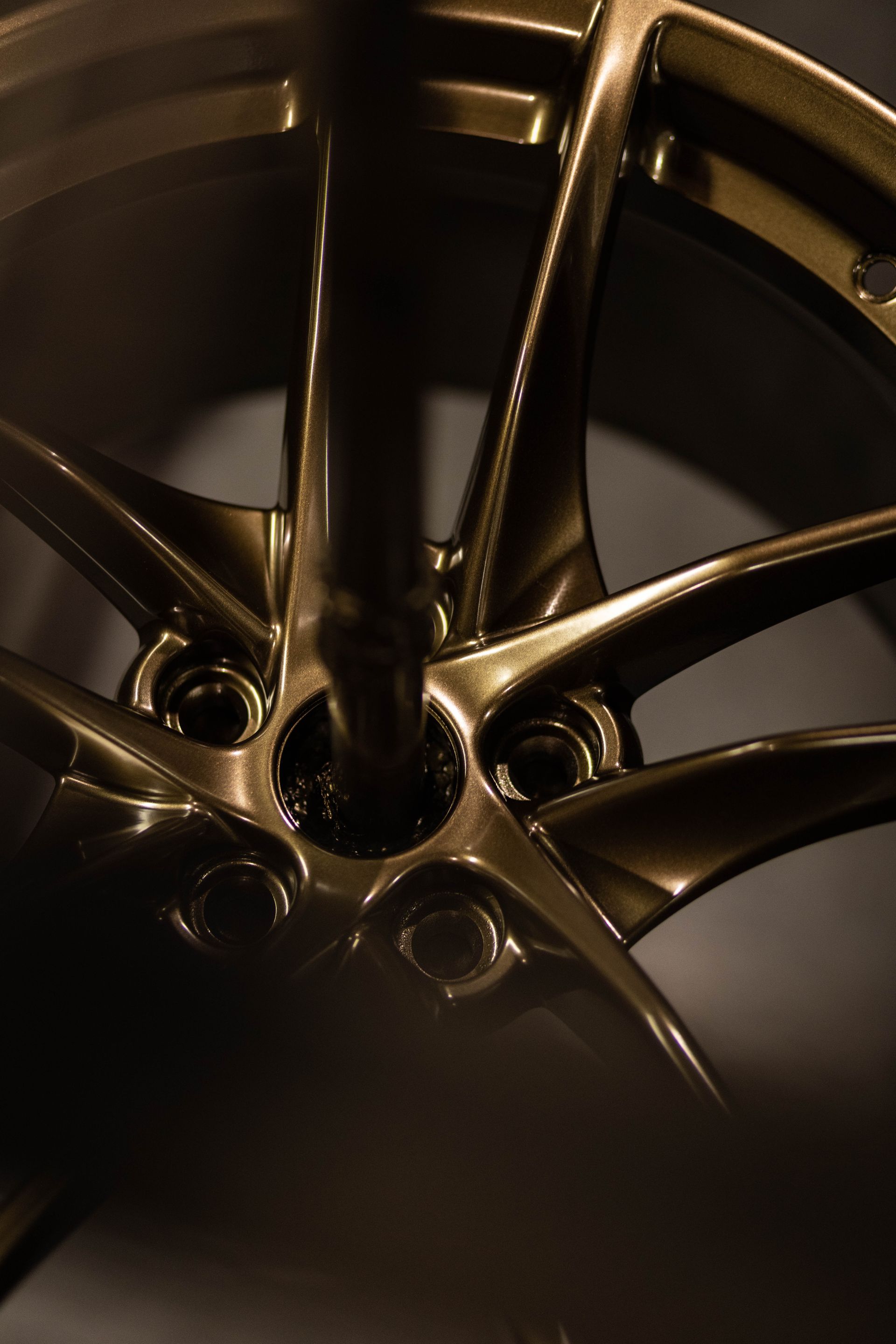 Close-up of a metallic car wheel rim with gold spokes and dark center shadows
