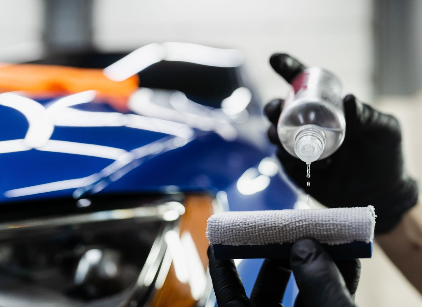 Detailing spray nozzle over a blue car during cleaning or polishing