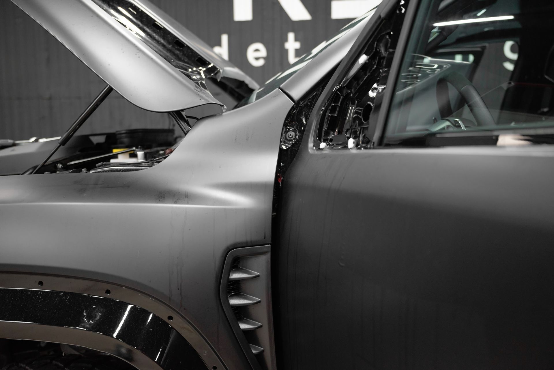Matte black SUV with hood open, shown close-up indoors at an auto show