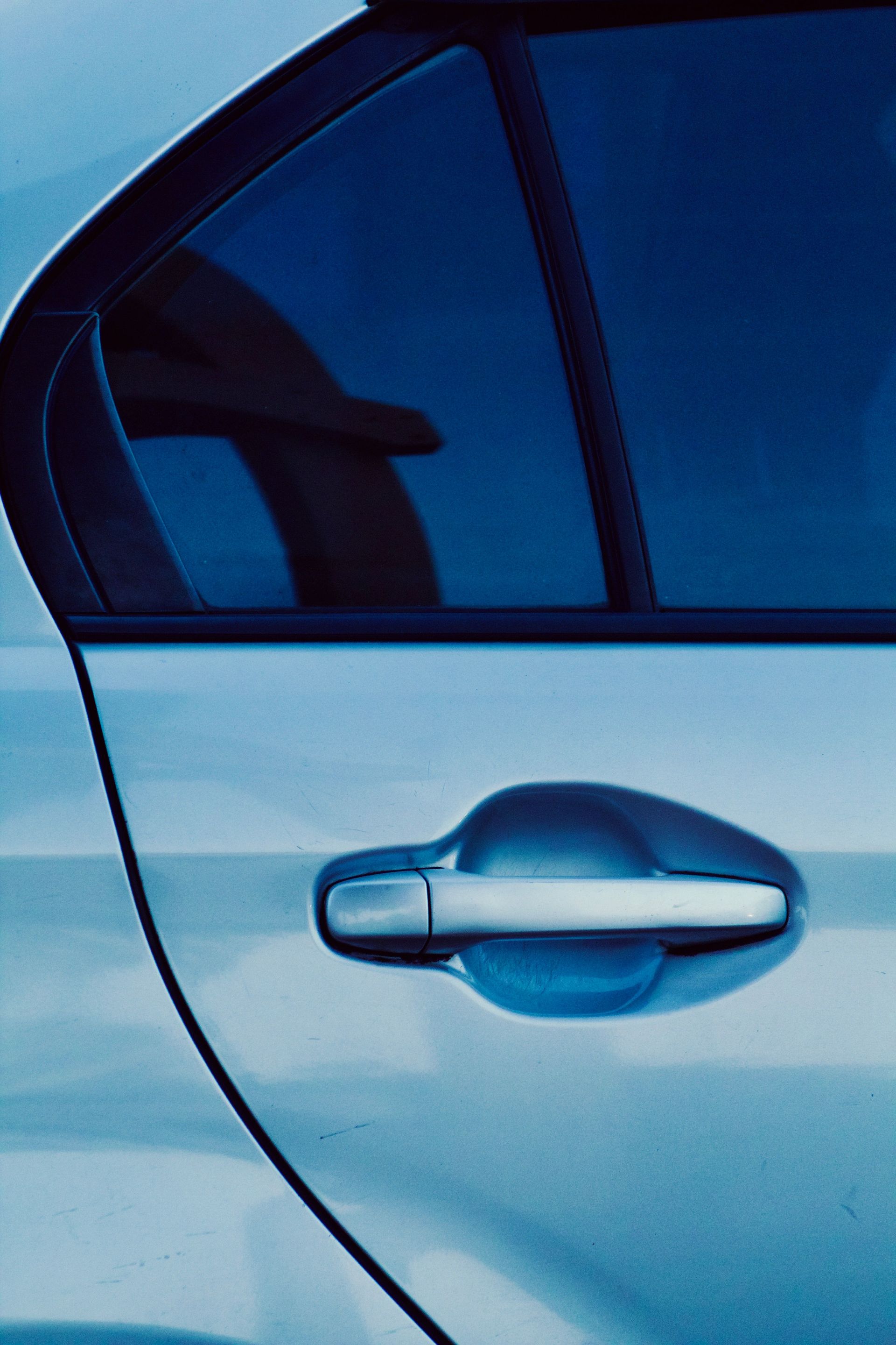 Gloved hand polishing a black car’s rear panel near the red taillight