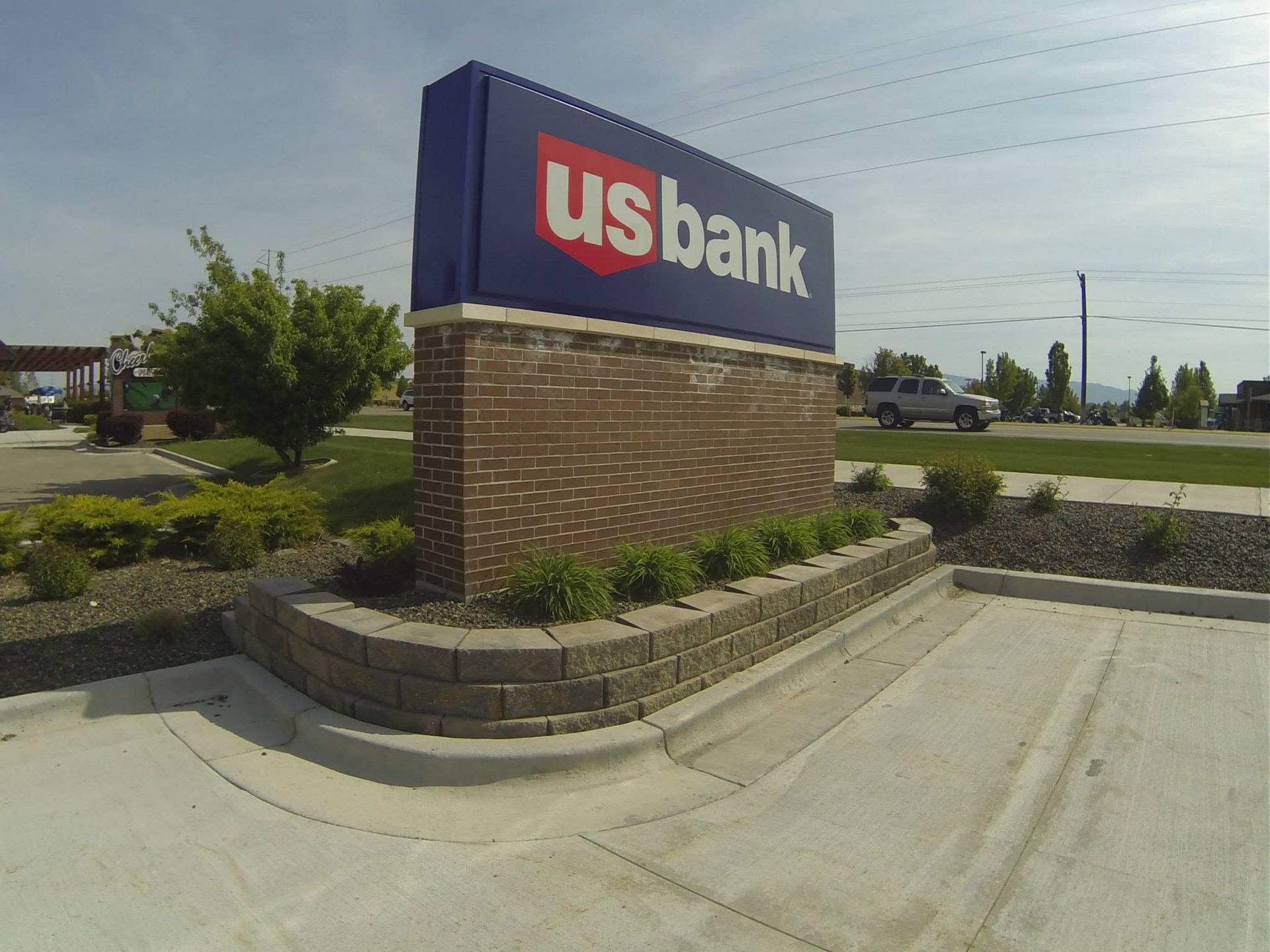 US Bank sign on a brick base beside a parking lot under a clear sky
