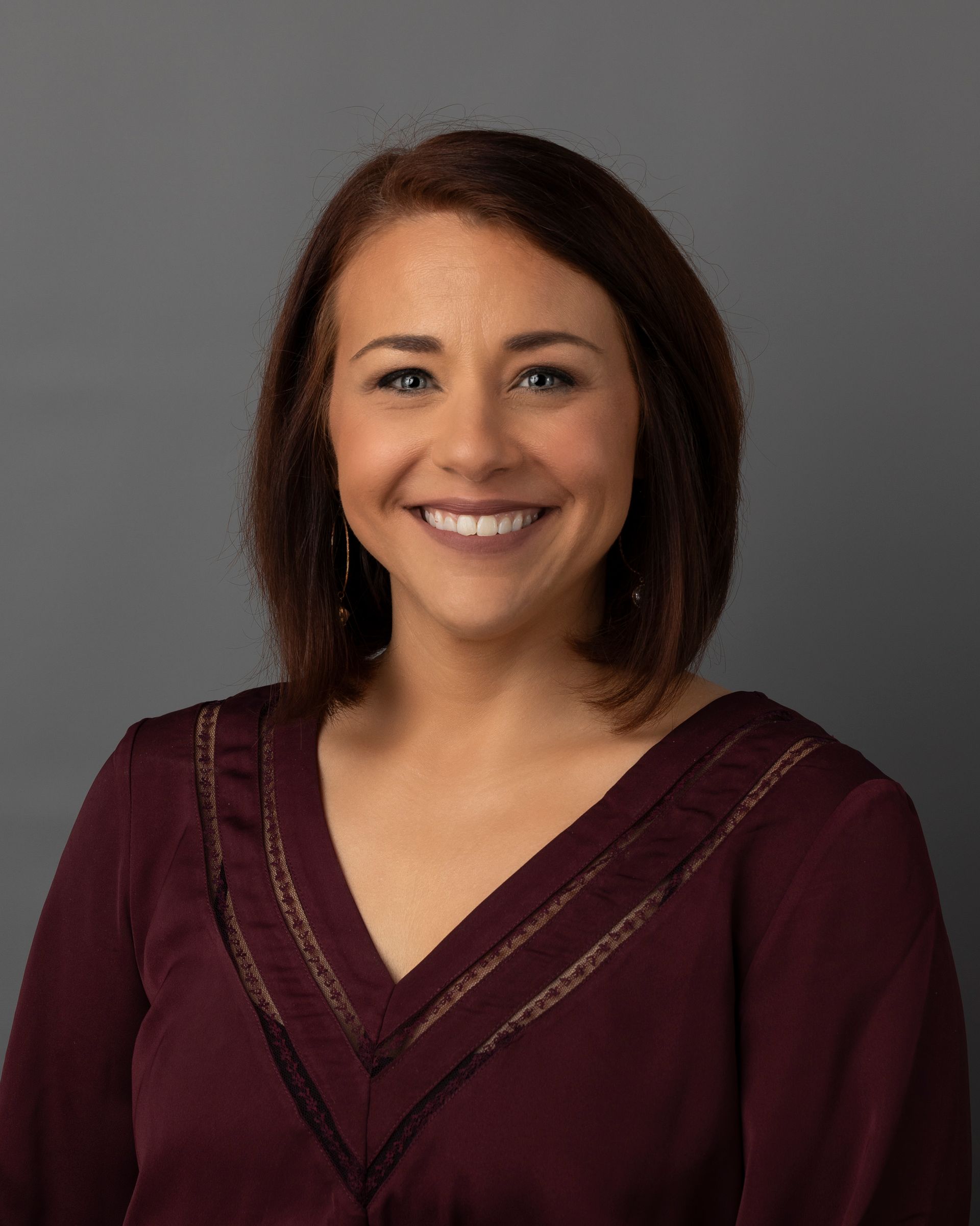 a woman in a maroon shirt is smiling for the camera