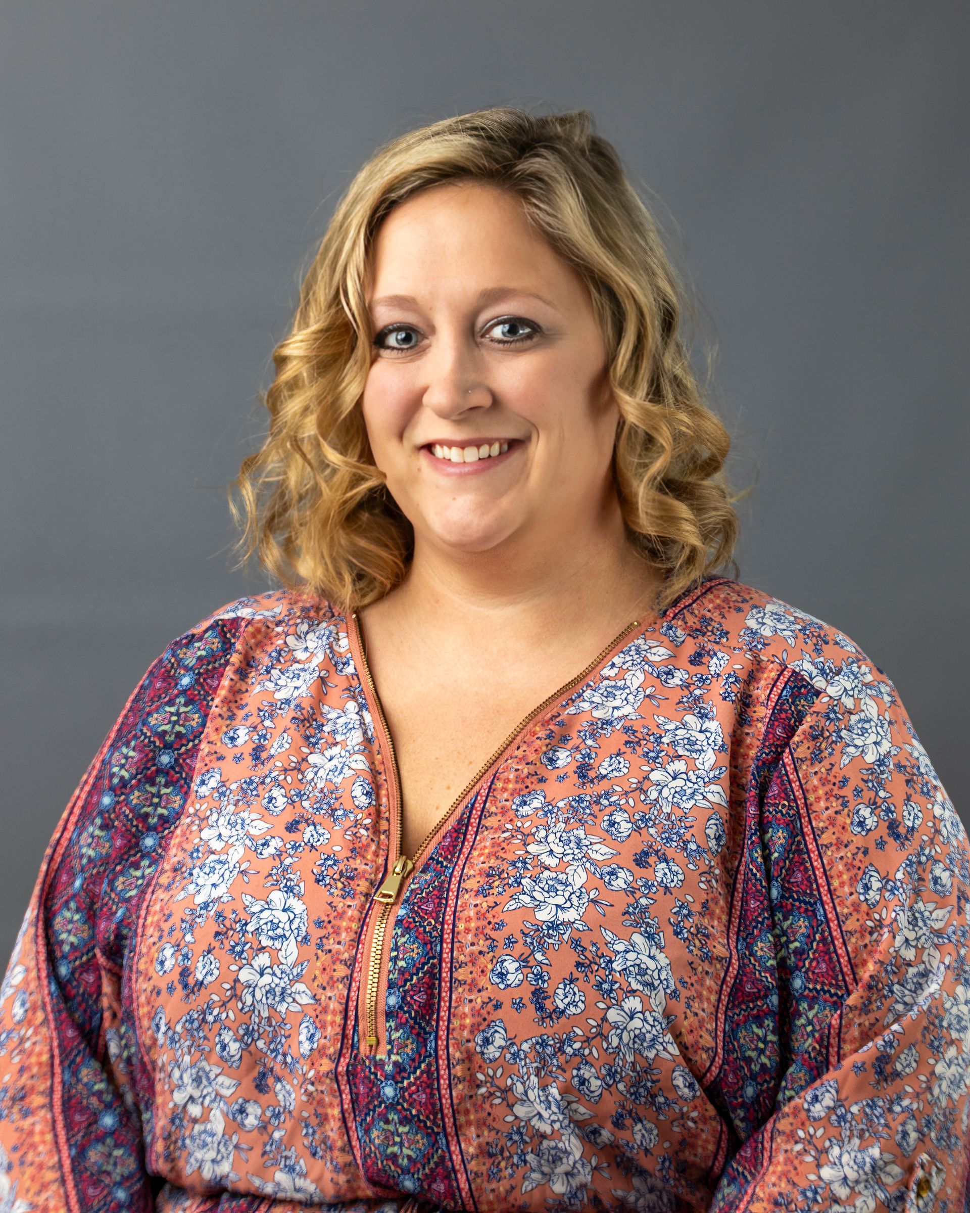 a woman in a floral shirt is smiling for the camera .