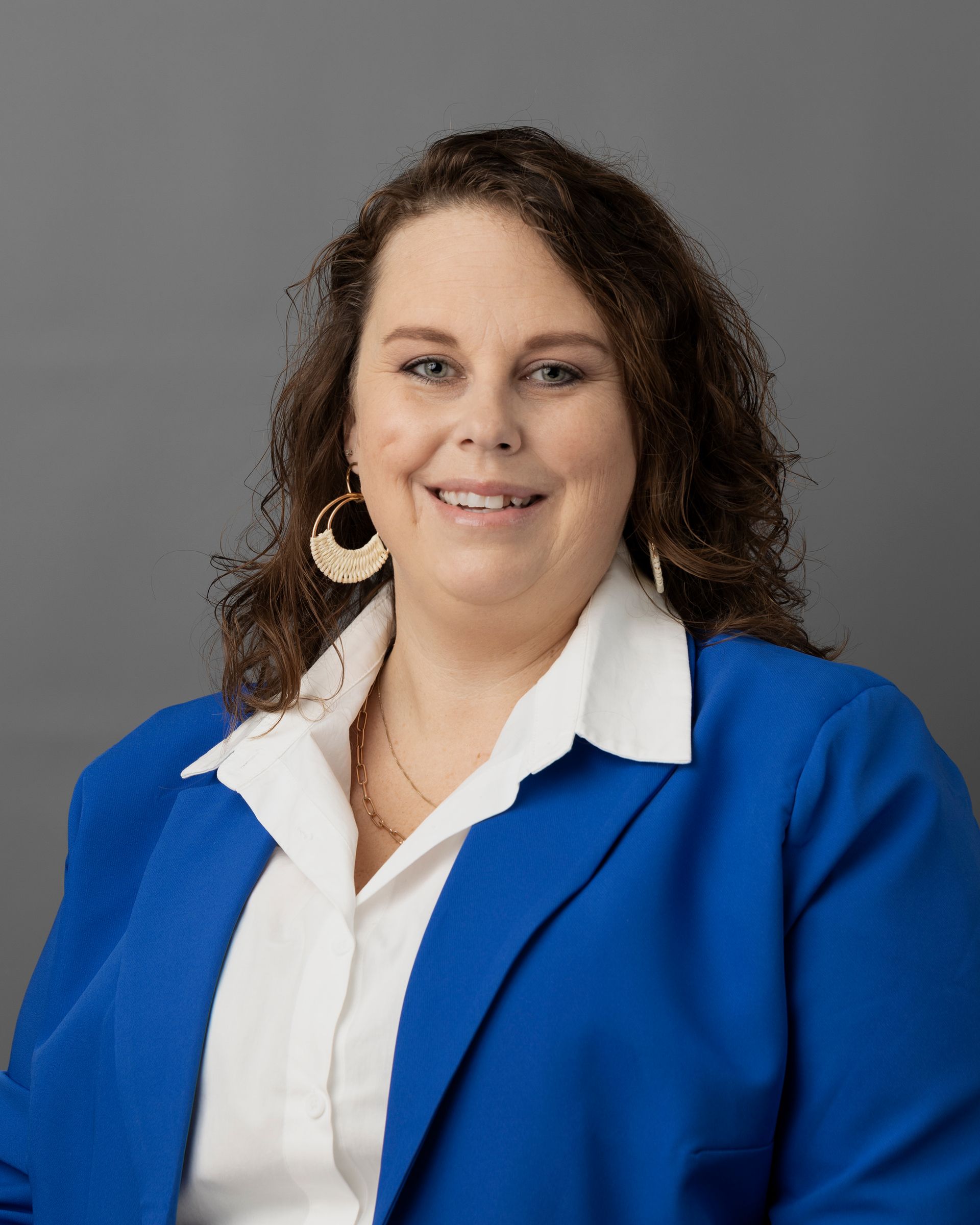 a woman in a blue jacket and white shirt smiles for the camera