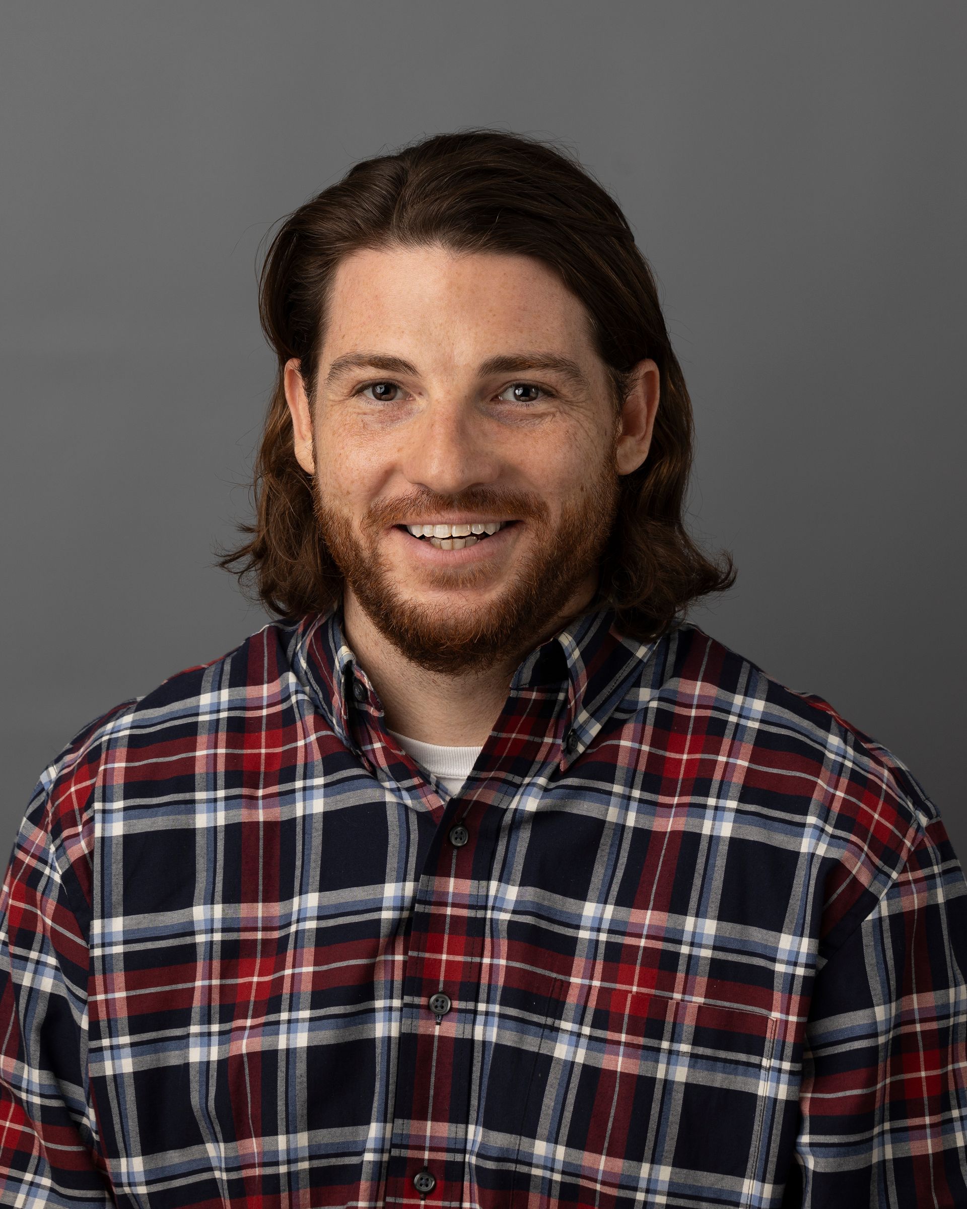 a man with a beard is wearing a plaid shirt and smiling .