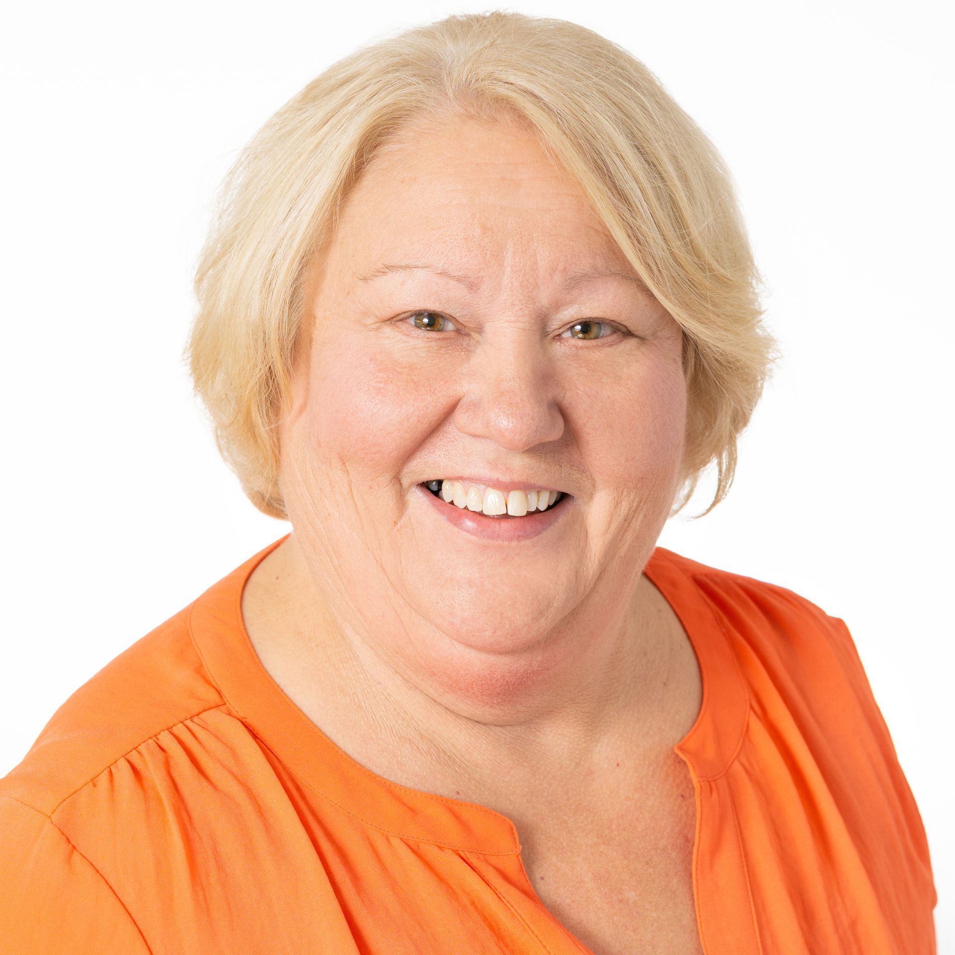 a woman wearing an orange shirt is smiling for the camera