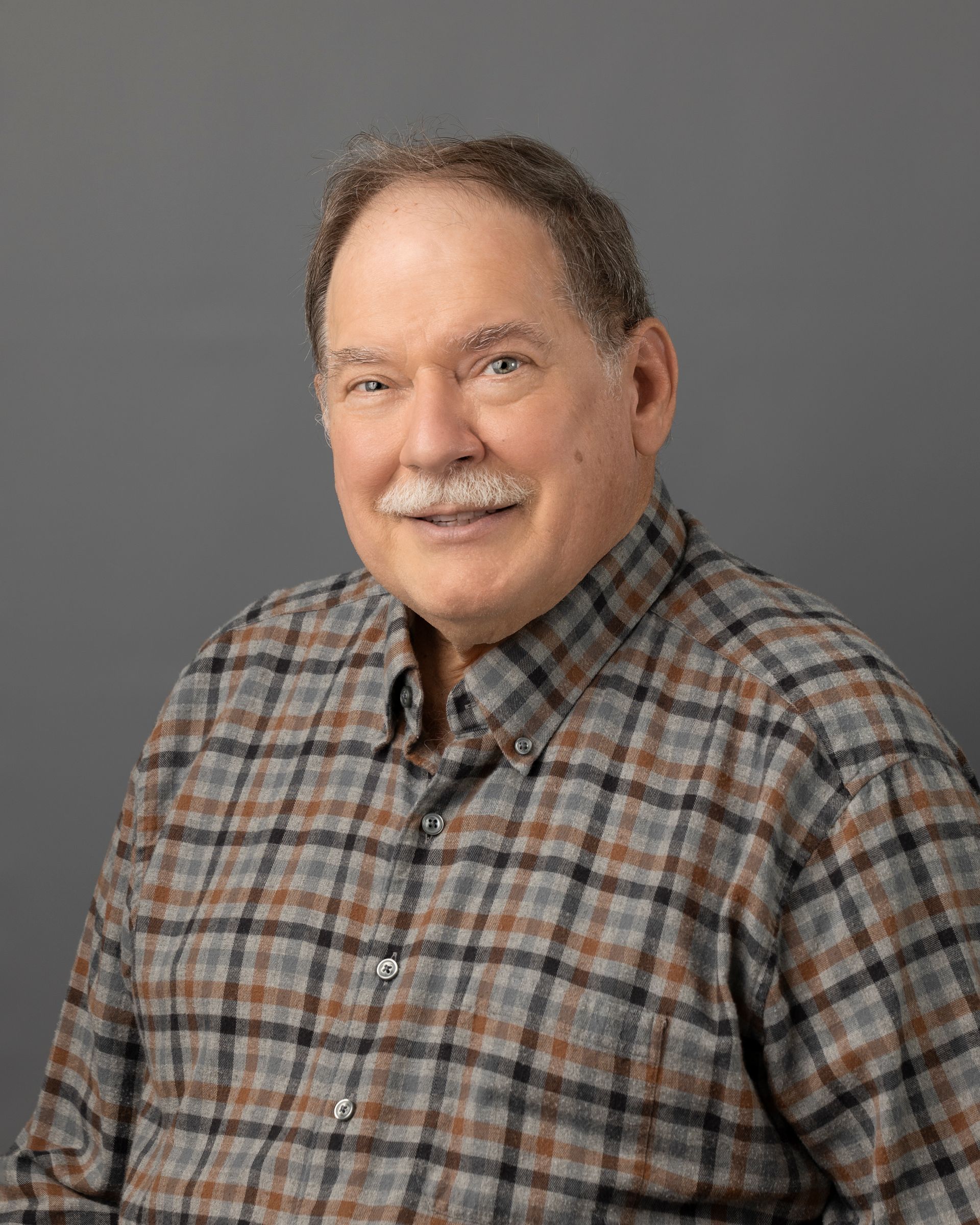 a man in a plaid shirt is smiling for the camera .