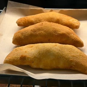 Tre calzoni dorati, cotti al forno, su una teglia rivestita di carta da forno.