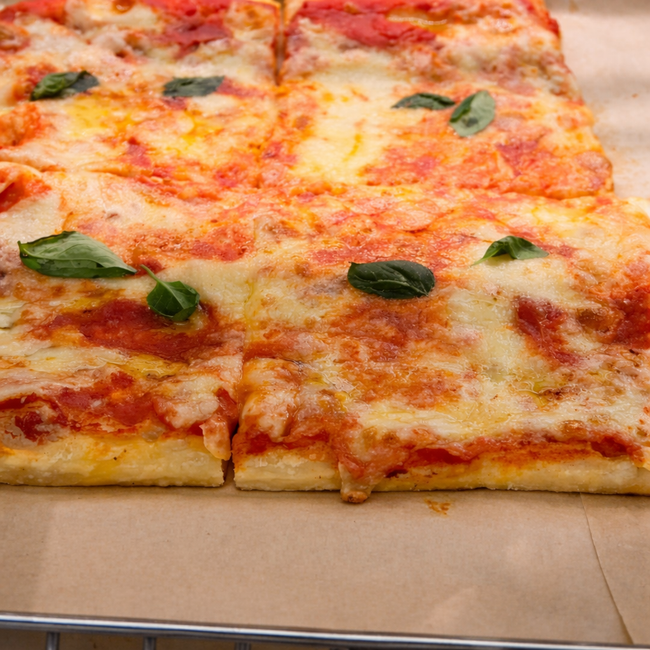 Fette quadrate di pizza al formaggio con salsa di pomodoro e basilico sopra.