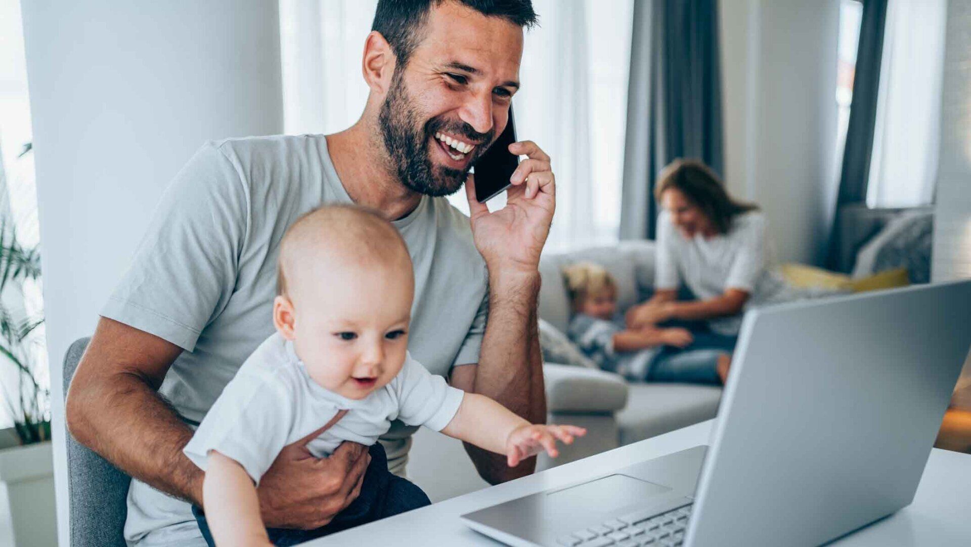 A Man On A Call Holding His Child — United States — NextGen Financial Advice A Man On A Call Holding His Child — United States — NextGen Financial Advice