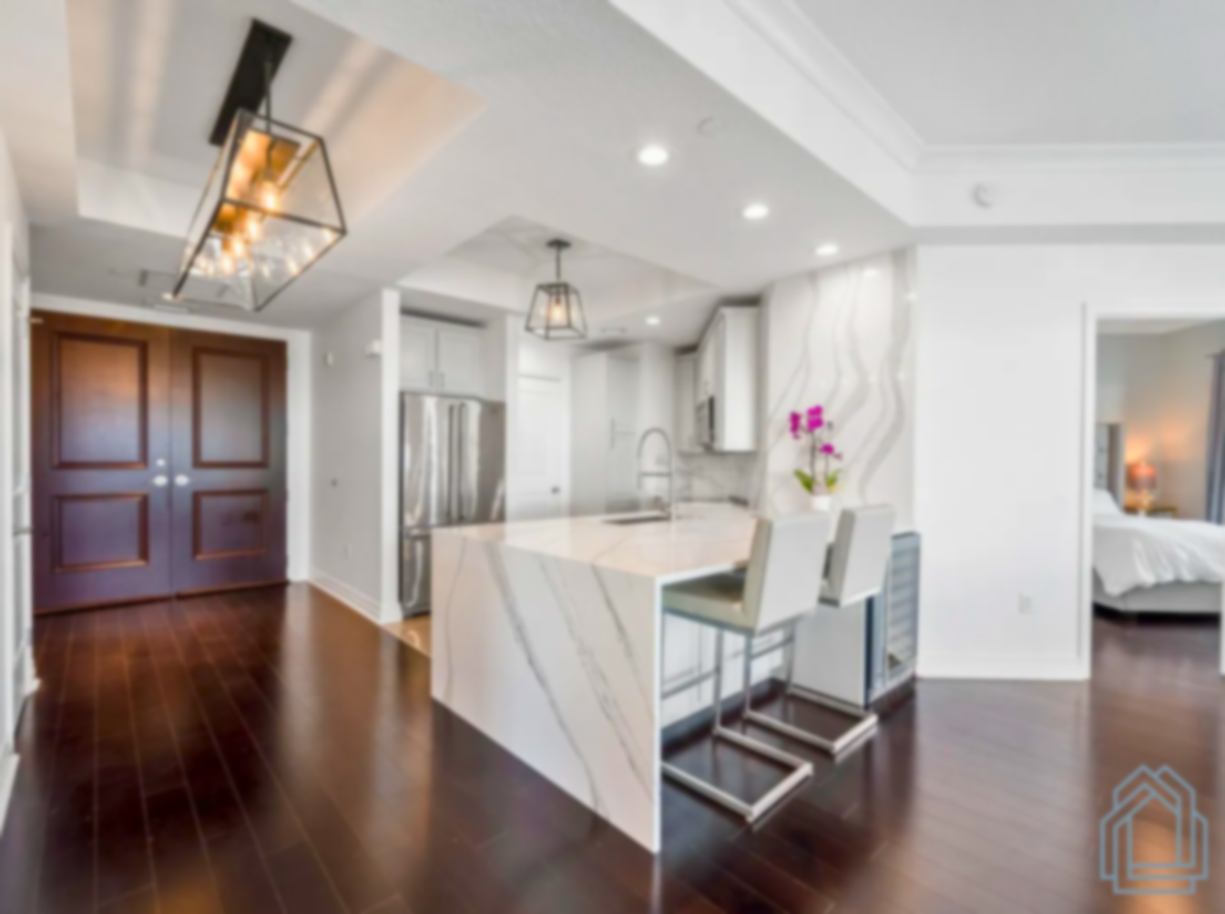 Bright modern kitchen with white island, stainless appliances, dark wood floors, and pendant lights