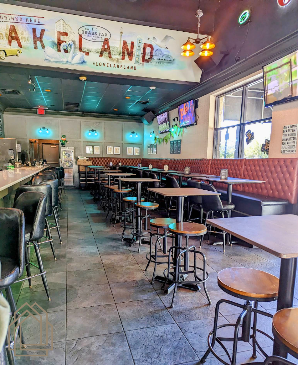 Empty retro diner interior with checkered floor, stools, booths, and “TAKE LAND” sign