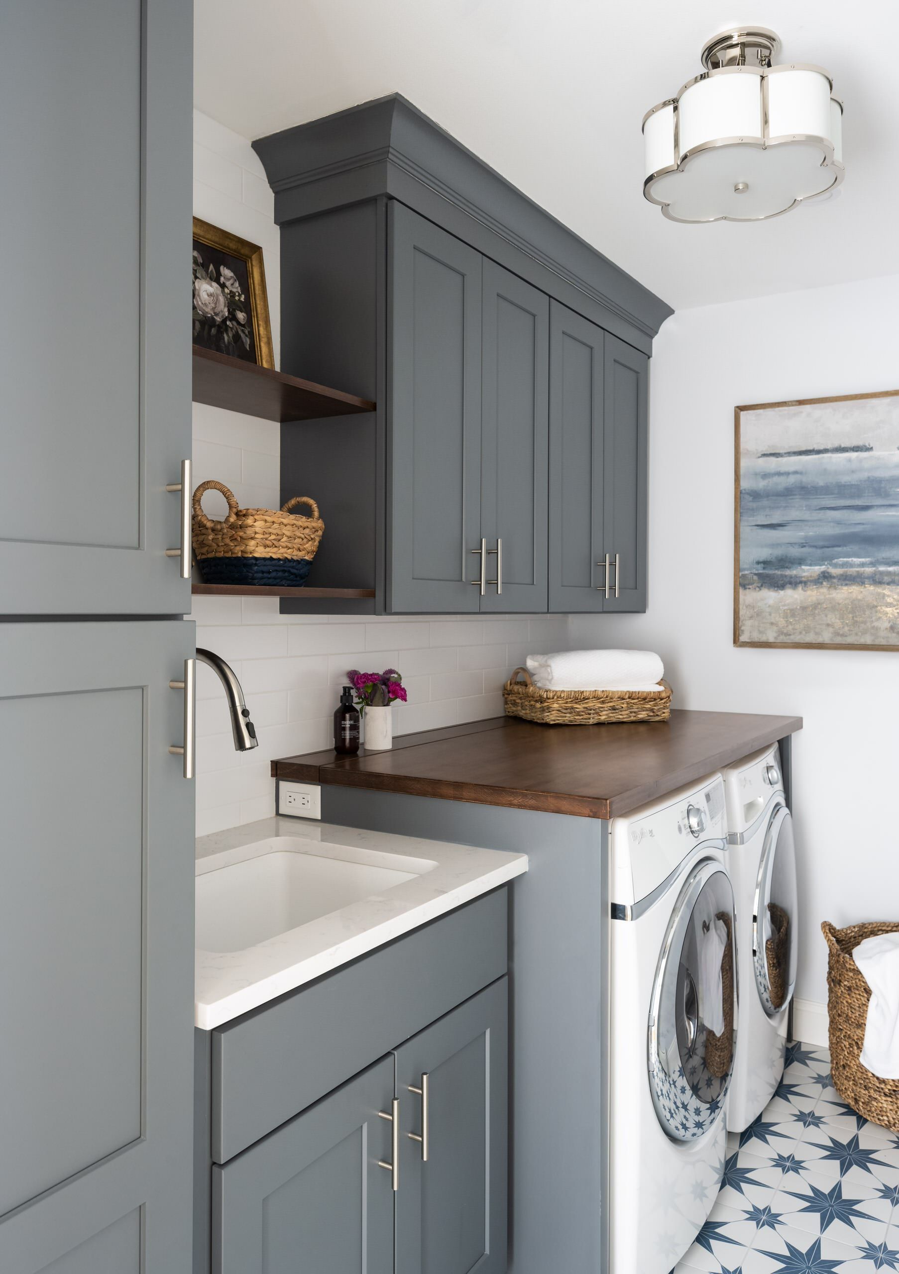 Laundry room with gray cabinets, wood countertop, washer, and blue patterned tile floor