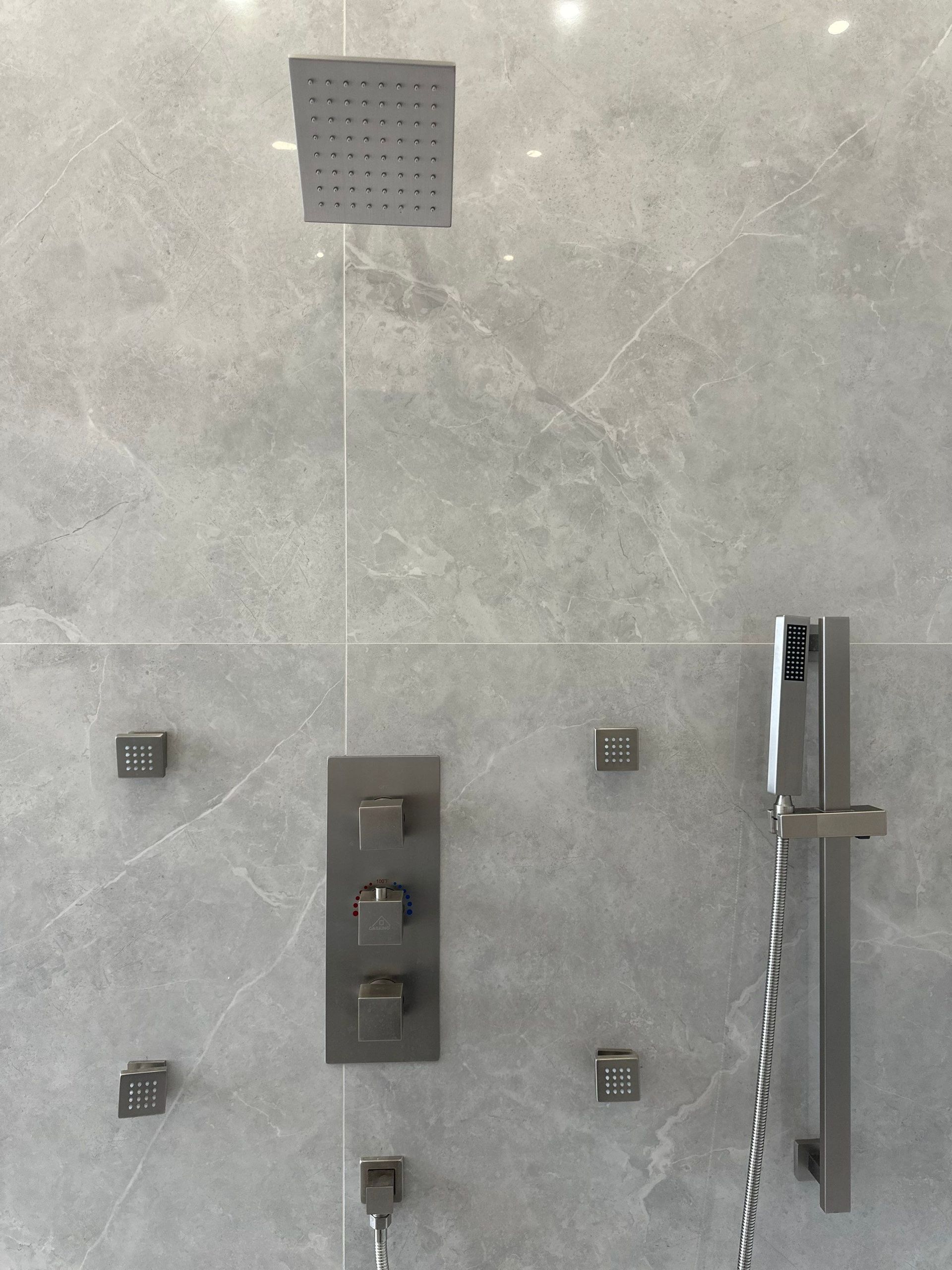 Modern gray shower wall with overhead rain shower, body jets, faucet, and handheld sprayer