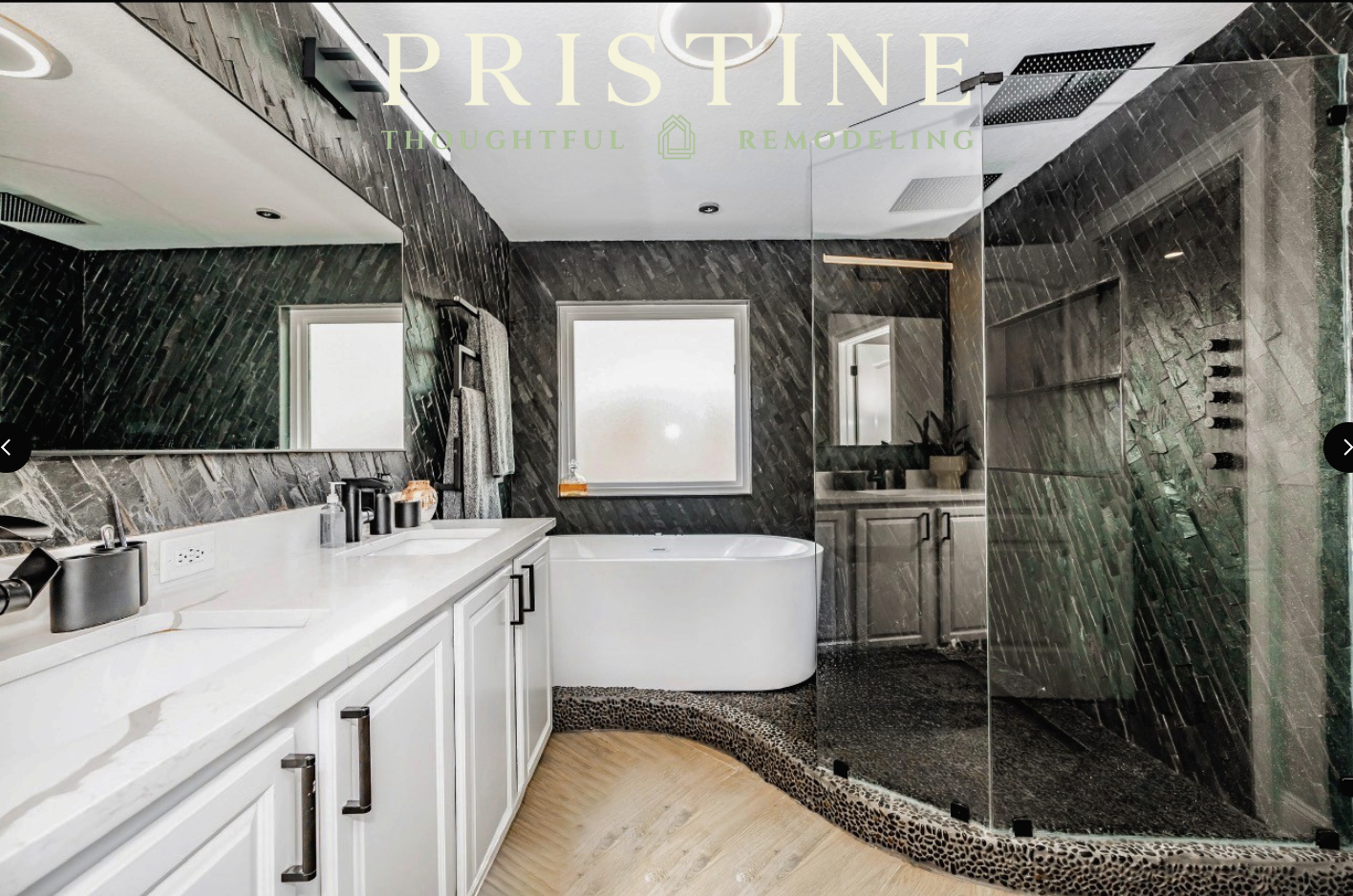 Modern bathroom with white vanity, freestanding tub, glass shower, and dark tiled walls