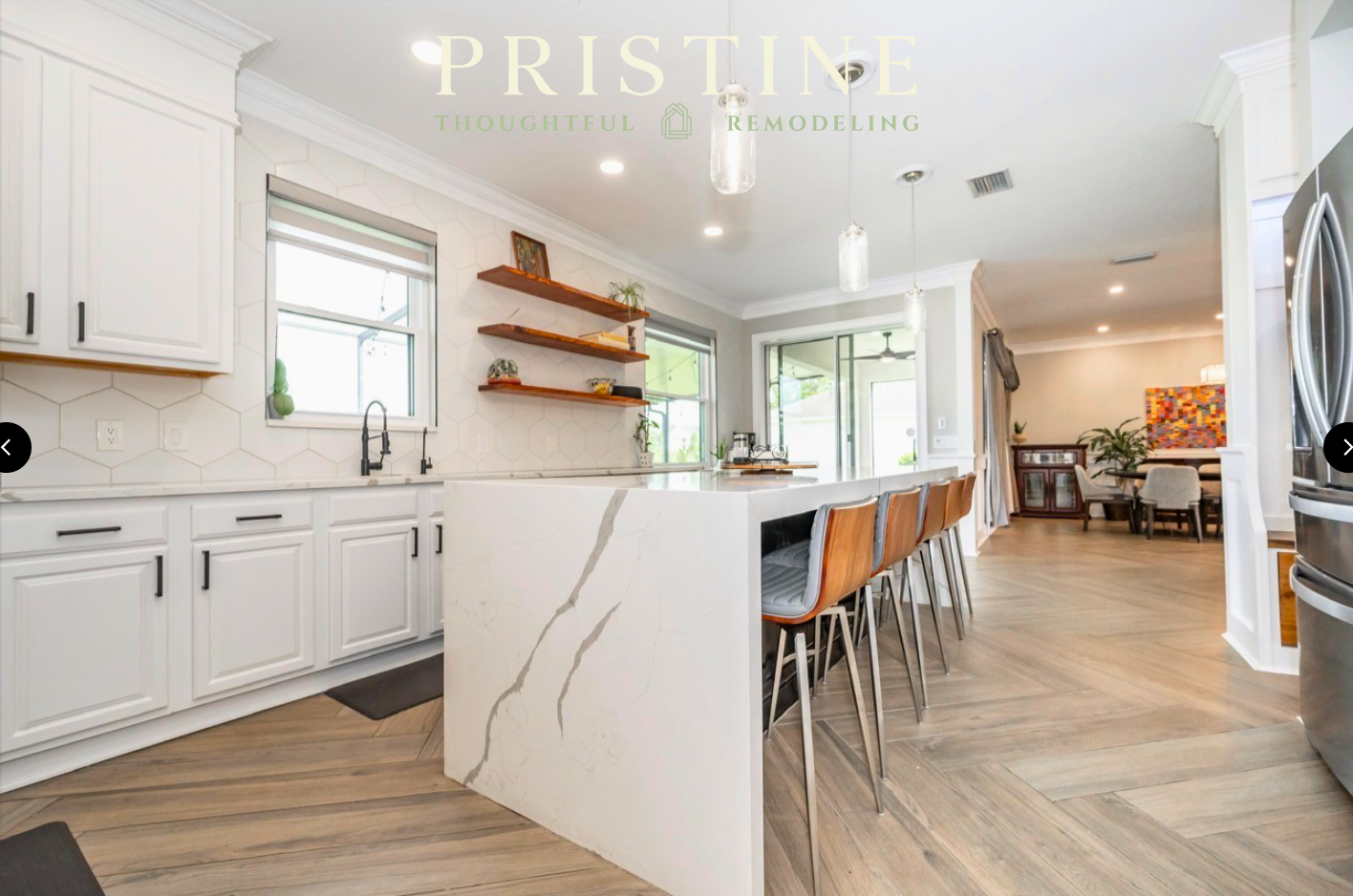 Bright modern kitchen with white cabinets, marble island, and wood floors