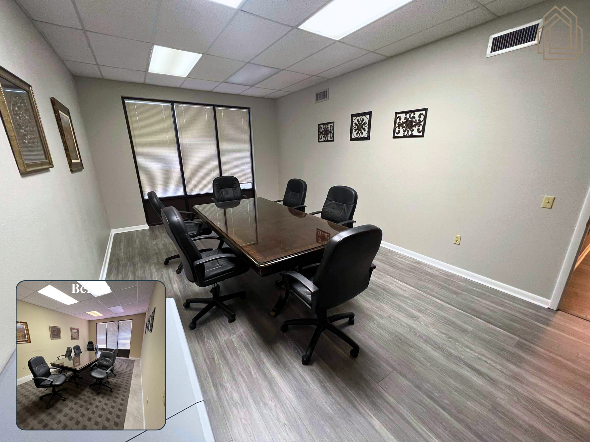 Small office conference room with a long table, black chairs, wall art, and a window with blinds.