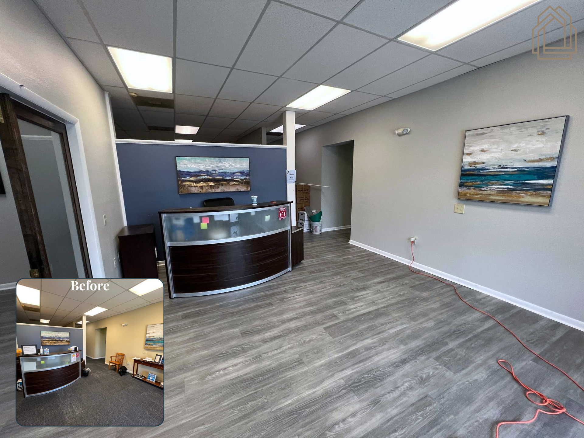 Modern office lobby with reception desk, wall art, gray flooring, and fluorescent ceiling lights