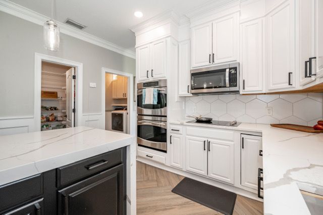 Bright white modern kitchen with island, built-in oven, microwave, and light wood floor