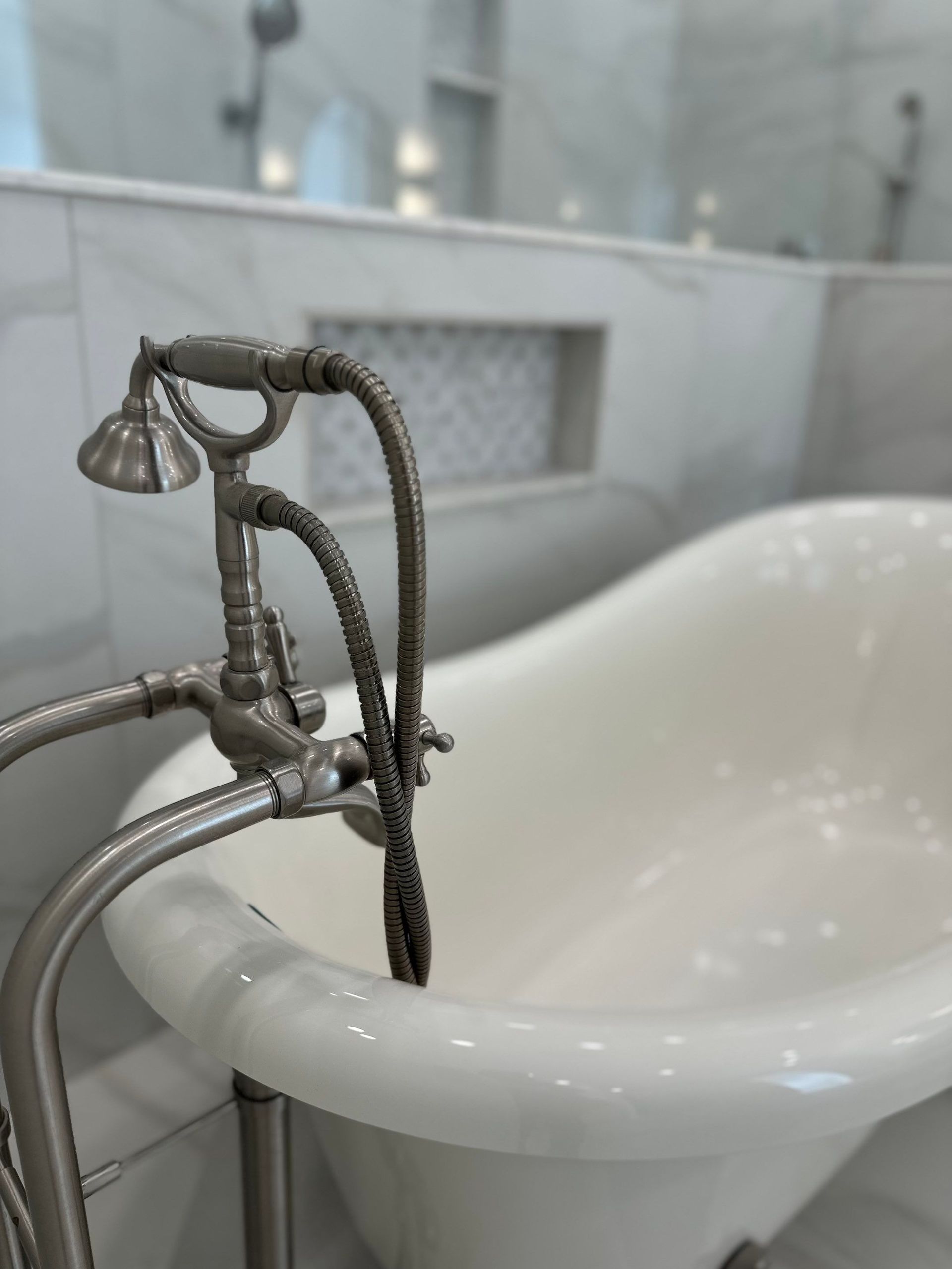 Vintage-style faucet filling a white clawfoot bathtub in a bright bathroom
