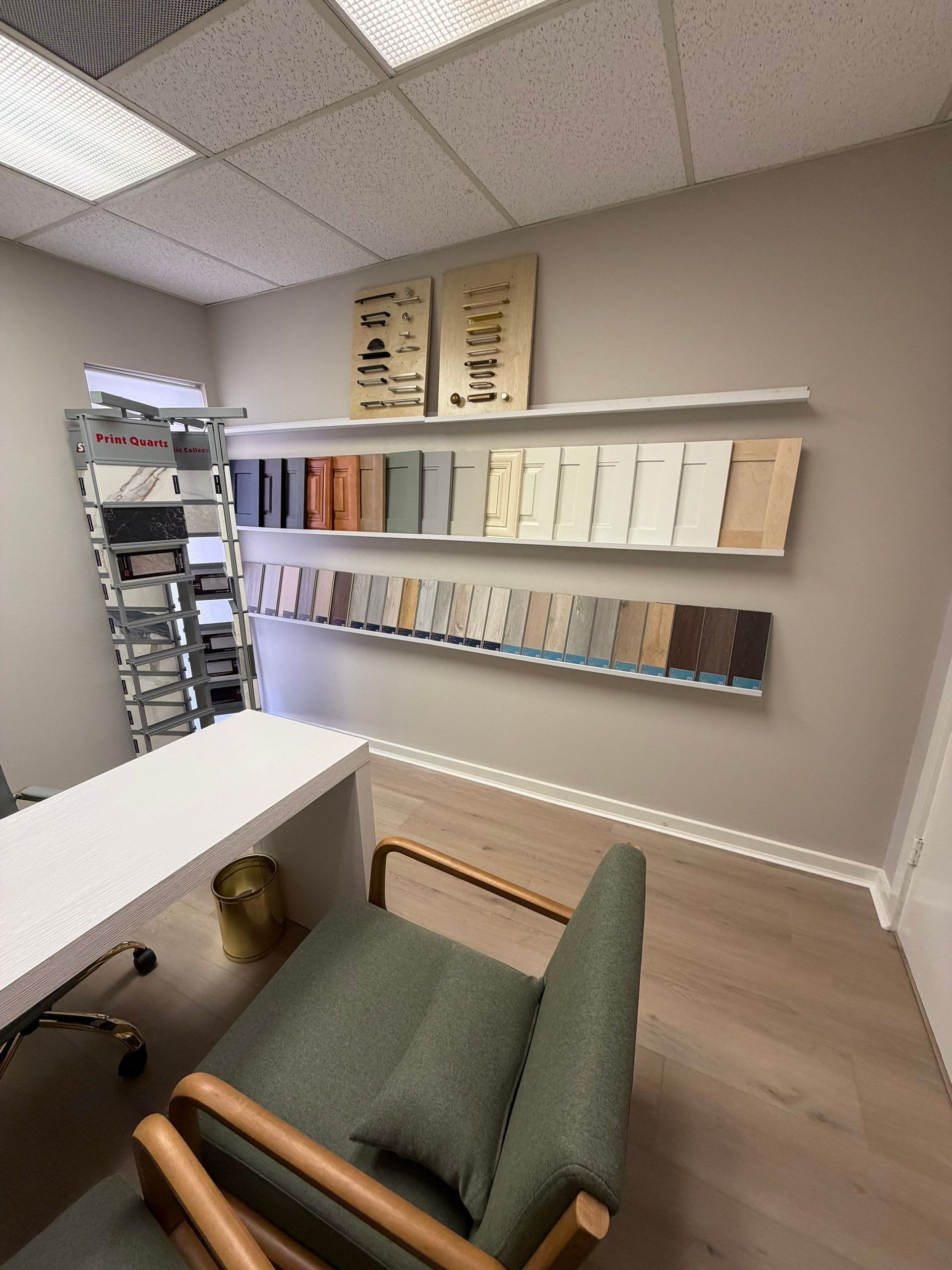 Modern waiting room with green chair, white walls, sample display shelves, and ceiling lights.