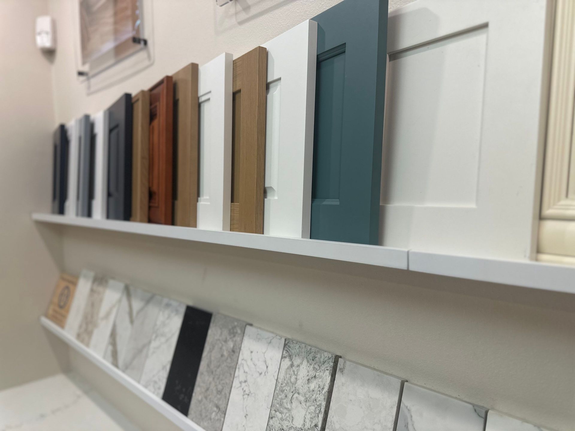 Display of paint and tile samples on white wall shelves in a showroom