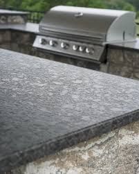 Rain-speckled dark stone countertop with a stainless steel grill blurred in the background.