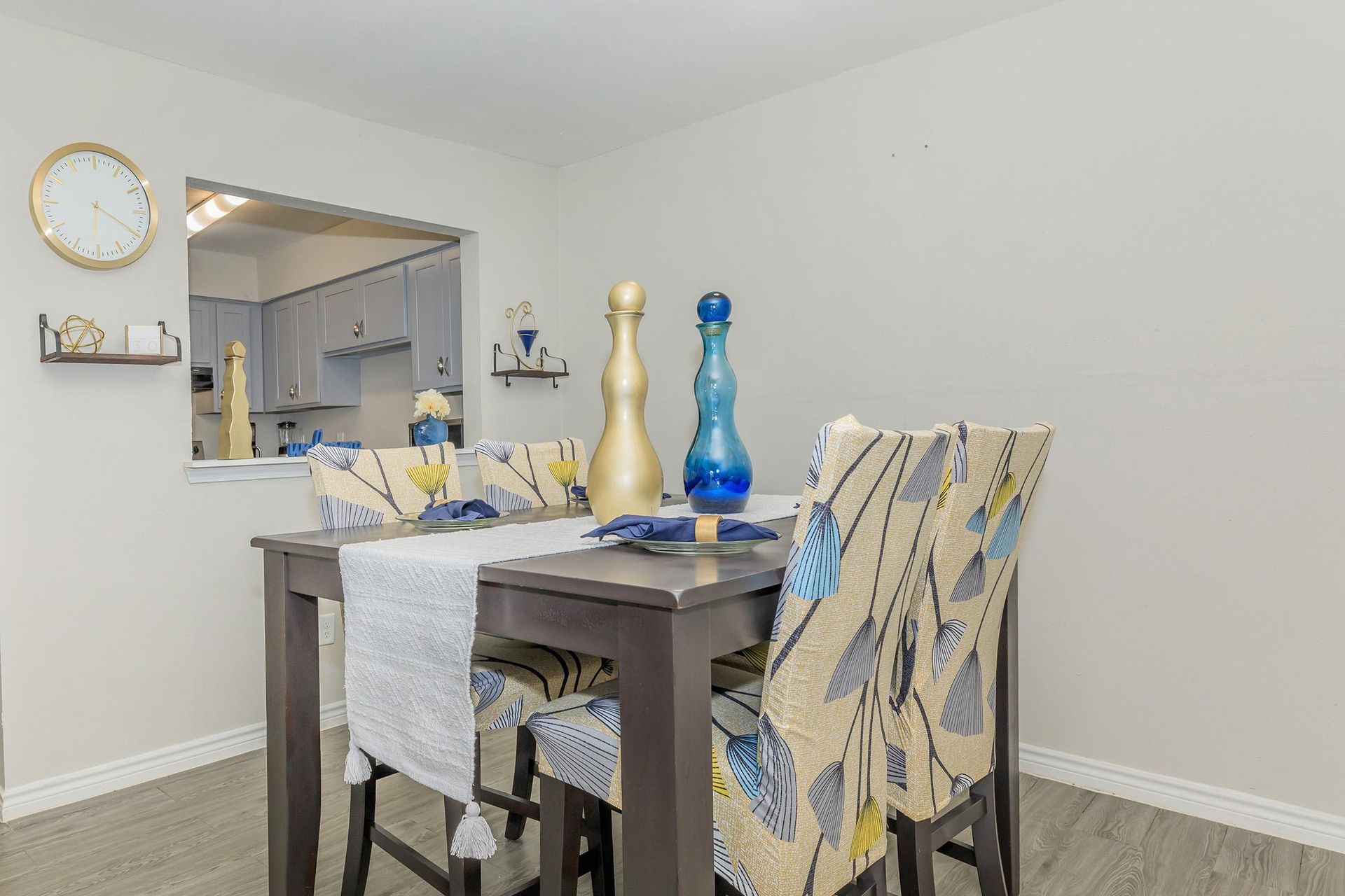 Dining area with a dark wood table and patterned chairs, open to a kitchen.