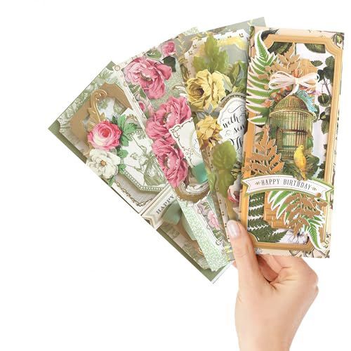 Hand holding three floral greeting cards with green, pink, and gold botanical designs