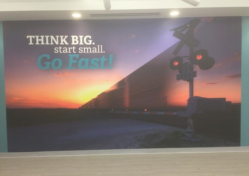 Billboard with sunrise railroad scene and slogan “Think big. Start small. Go fast!”