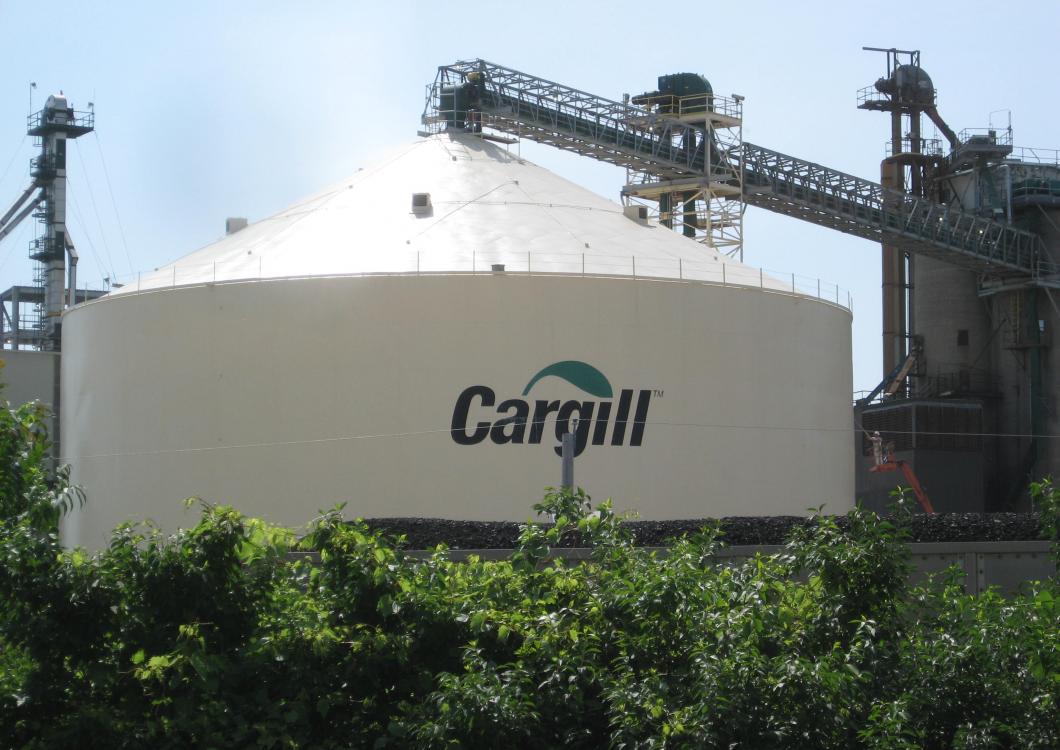 Cargill industrial storage tank with piping and greenery in the foreground