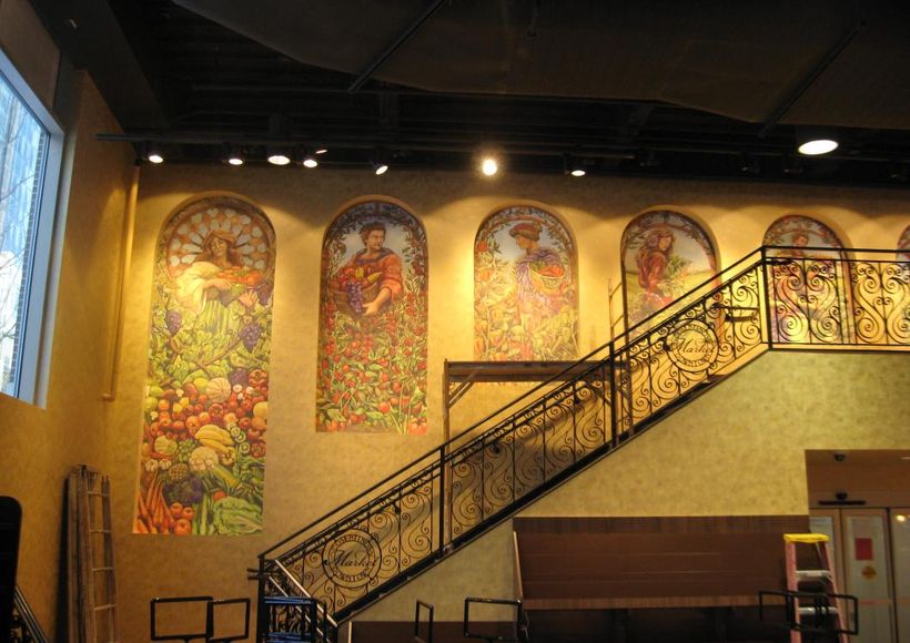 Interior with stained-glass murals and a staircase in a warmly lit hall
