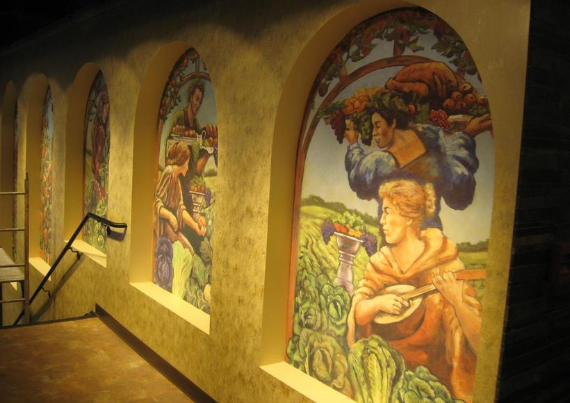 Gallery hallway with arched mural paintings in warm earth tones on textured walls