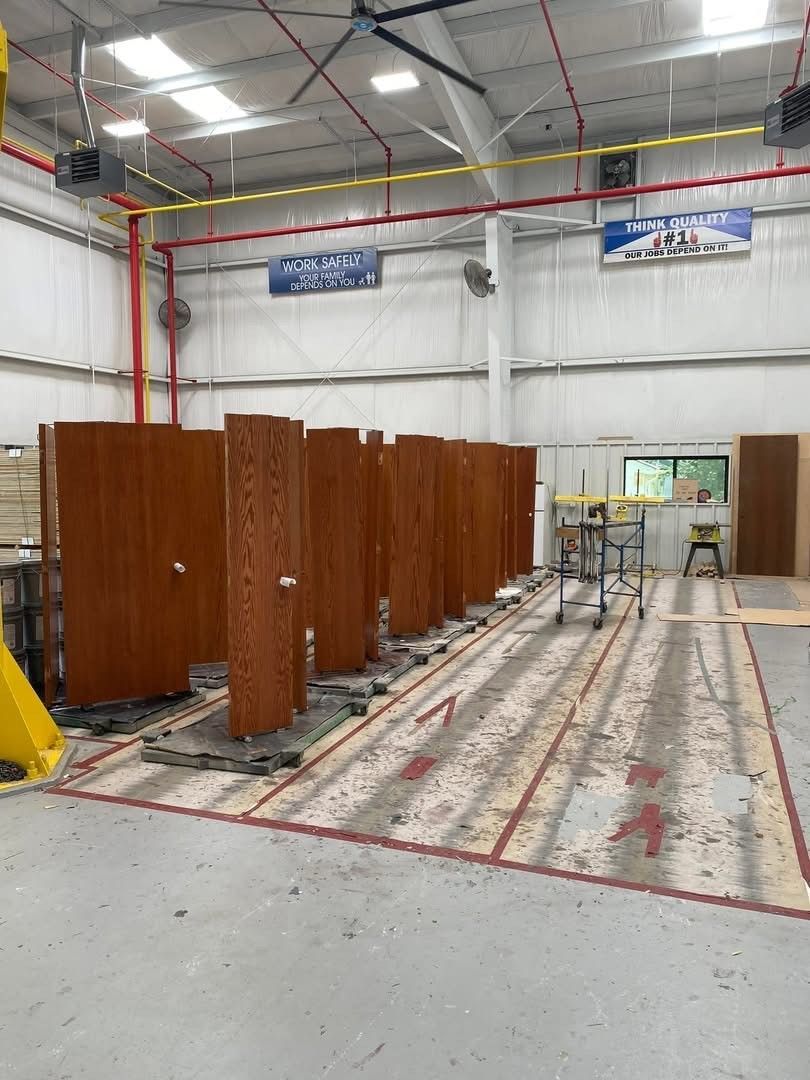 Indoor workshop with rows of tall brown wooden panels and a cart on a marked concrete floor