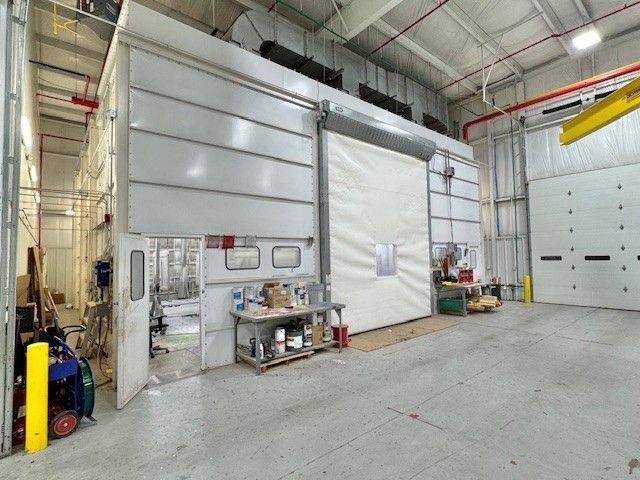 Industrial warehouse interior with large white rolling door, metal shelves, and concrete floor