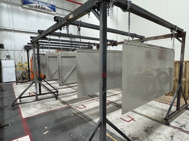 Industrial spray booth with hanging gray panels in a workshop