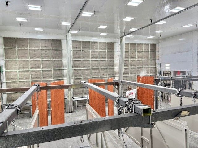 Industrial facility with orange machinery and metal rails inside a bright room with large windows.